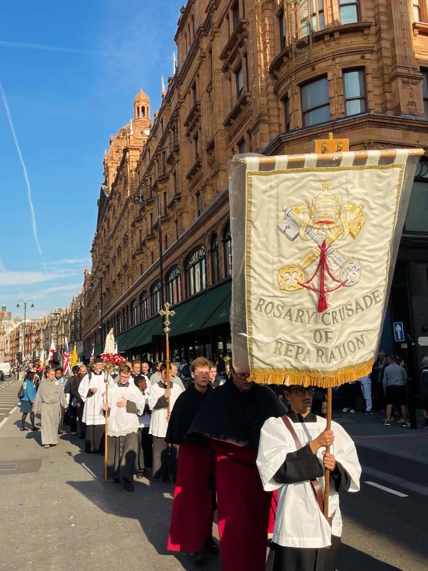 Rosary Crusade procession passing Harrods in London, led by clergy carrying the Rosary Crusade of Reparation banner